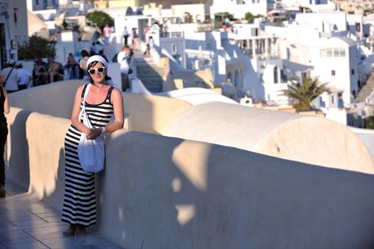 Beautiful young Greek woman in fashion clothes have fun at n the streets of Oia, Santorini, Greece