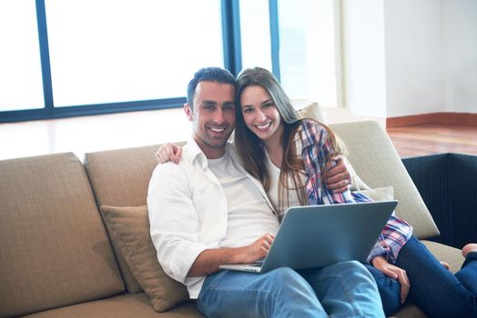 happy young relaxed  couple working on laptop computer at modern home interior