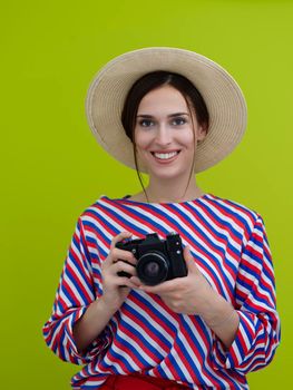 Portrait of beautiful female photographer close up. Say cheese. Young smiling woman holding camera and thinking how to make photo isolated on green background.