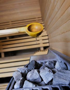 wooden luxury sauna indoor with hot stones and falling splashing water