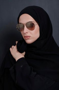 Young muslim businesswoman in traditional clothes or abaya and sunglasses posing in front of black chalkboard. Arab woman representing modern arabic lifestyle, islamic  fashion and Ramadan kareem concept