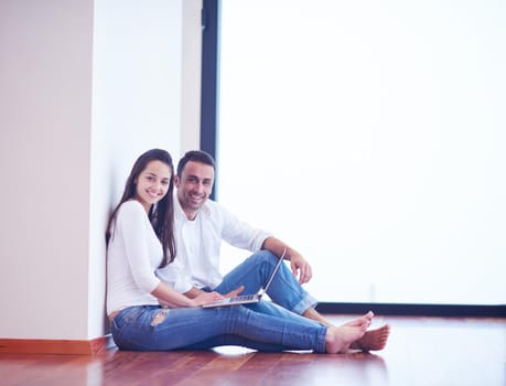 happy young relaxed  couple working on laptop computer at modern home interior