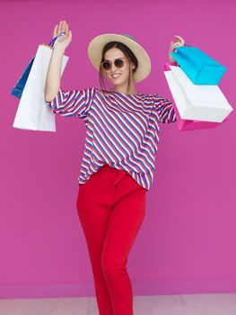 Young woman with shopping bags on pink background. Happy girl posing with new purchases after a day of big sale. Black Friday concept