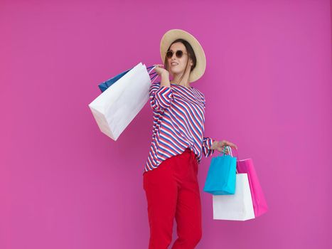 Young woman with shopping bags on pink background. Happy girl posing with new purchases after a day of big sale. Black Friday concept