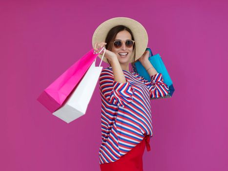 Young woman with shopping bags on pink background. Happy girl posing with new purchases after a day of big sale. Black Friday concept