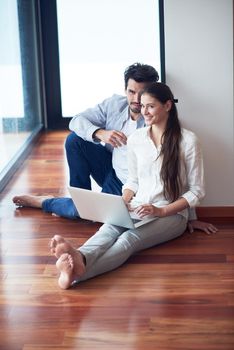 happy young relaxed  couple working on laptop computer at modern home interior