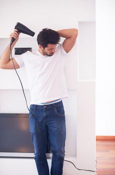 young handsome nude man at home using  hair  hairdryer