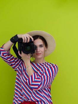 Portrait of beautiful female photographer shooting close up. Say cheese. Young smiling woman holding camera isolated on green background