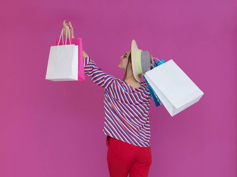 Young woman with shopping bags on pink background. Happy girl posing with new purchases after a day of big sale. Black Friday concept