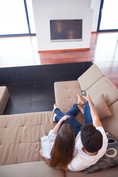 Relaxed young couple watching tv at home in bright living room