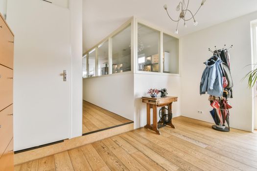 An adorable spacious hallway with a coat rack and a small wooden table