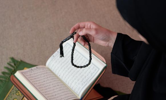 Sarajevo, Bosnia and Herzegovina - May 28, 2019 Middle eastern woman praying and reading the holy Quran (public item of all muslims). Education concept of Muslim woman studying The holy Quran at home or mosque in ramadan month.