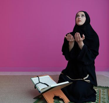 Sarajevo, Bosnia and Herzegovina - May 28, 2019 Middle eastern woman praying and reading the holy Quran (public item of all muslims). Education concept of Muslim woman studying The holy Quran at home or mosque in ramadan month.