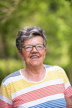 portrait of happy  senior woman with eyeglasses in nature