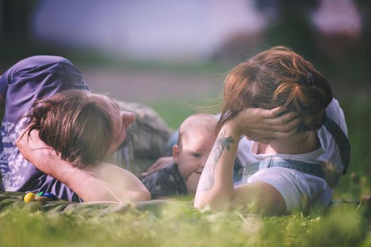 hipster family relaxing in park and playing with baby on beautiful sunny spring day