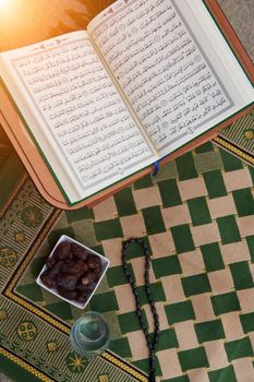 Sarajevo, Bosnia and Herzegovina - May 28, 2019  Iftar time Dried Dates, Holy Quran glass of water and tasbih on praying  rug or sejadah in Ramadan concept of Islamic education