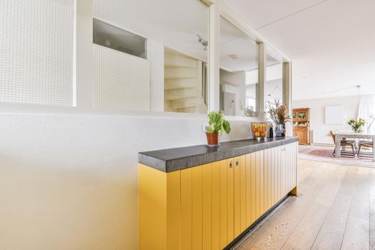 A lovely corridor with a yellow cabinet and a flower in a pot