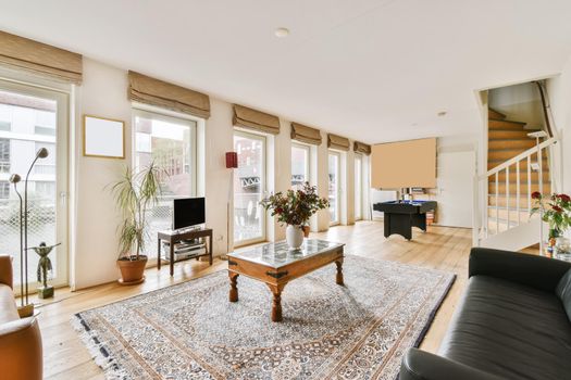 Lovely living room with black leather sofa and wooden coffee table