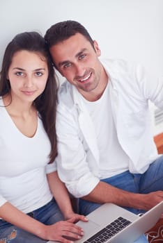 happy young relaxed  couple working on laptop computer at modern home interior