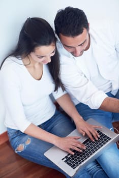 happy young relaxed  couple working on laptop computer at modern home interior