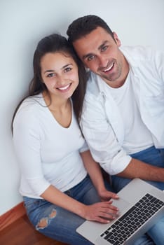 happy young relaxed  couple working on laptop computer at modern home interior