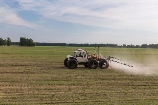 Tractor sprays liquid chemical fertilizers in corn field