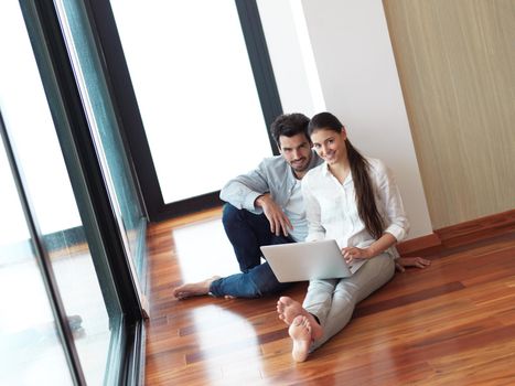 happy young relaxed  couple working on laptop computer at modern home interior