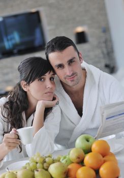 young family couple read newspaper at kitchen in morning with  fresh breakfast  fruits food and coffee drink on table