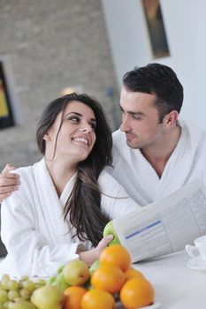 young family couple read newspaper at kitchen in morning with  fresh breakfast  fruits food and coffee drink on table