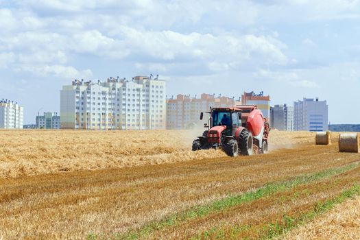 A round baler discharges a fresh wheat bale during harvesting.