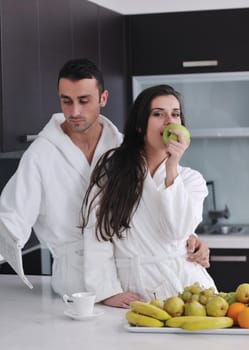 happy young couple have fun in  modern kitchen indoor  while preparing fresh fruits and vegetables food salad