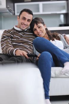 Relaxed young  couple watching tv at home in bright living room