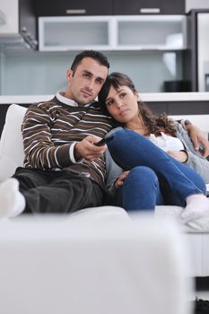 Relaxed young  couple watching tv at home in bright living room