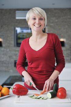 happy young  beautiful blonde  woman prepare food in  the kitchen at home