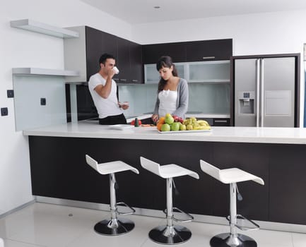 happy young couple have fun in  modern kitchen indoor  while preparing fresh fruits and vegetables food salad