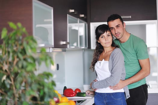 happy young couple have fun in  modern kitchen indoor  while preparing fresh fruits and vegetables food salad