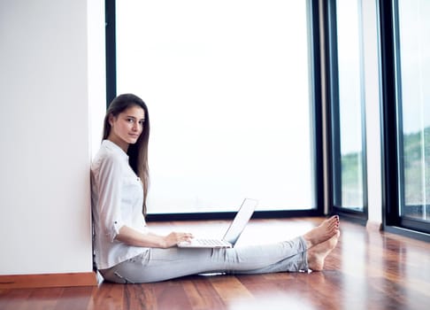 beautiful young woman relax and work on laptop computer modern  home office while listening musin on white headphones