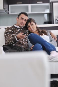 Relaxed young  couple watching tv at home in bright living room