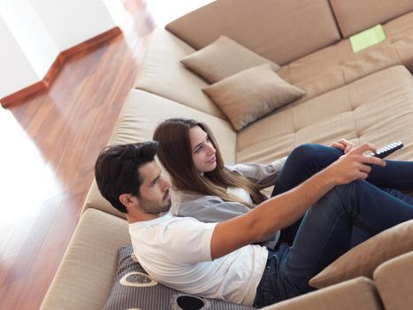 Relaxed young couple watching tv at home in bright living room