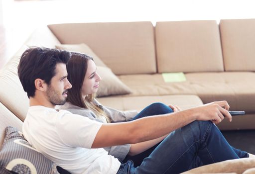 Relaxed young couple watching tv at home in bright living room