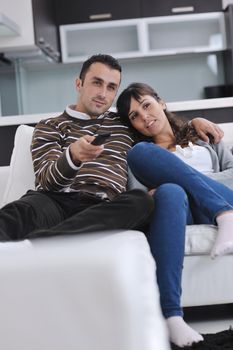 Relaxed young  couple watching tv at home in bright living room