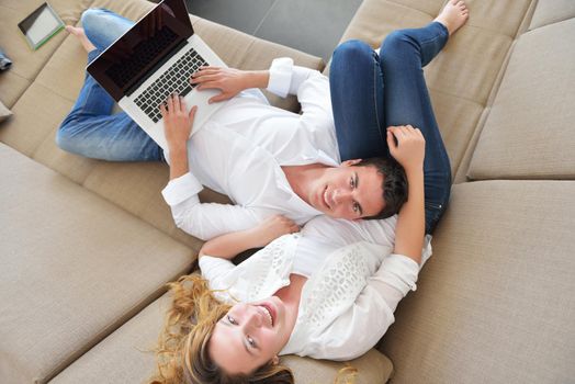 happy young relaxed couple working and playing on laptop computer at home