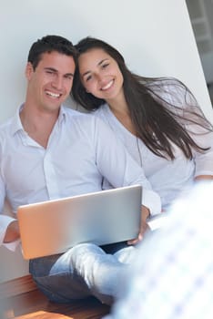 happy young relaxed couple working and playing on laptop computer at home