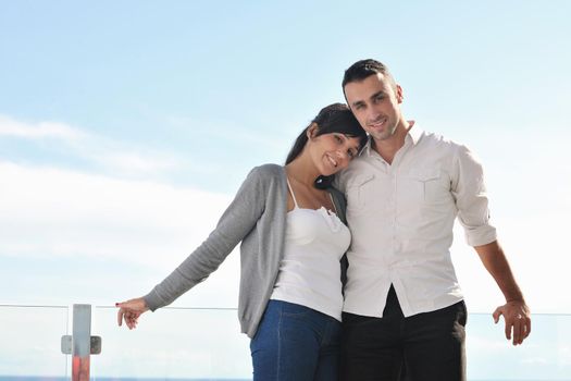 happy young couple relax on balcony outdoor with ocean and blue sky in background