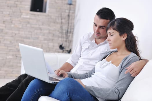 joyful couple relax and work on laptop computer at modern living room indoor home