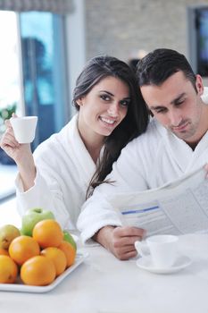 young family couple read newspaper at kitchen in morning with  fresh breakfast  fruits food and coffee drink on table