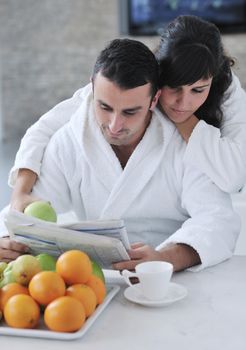 young family couple read newspaper at kitchen in morning with  fresh breakfast  fruits food and coffee drink on table