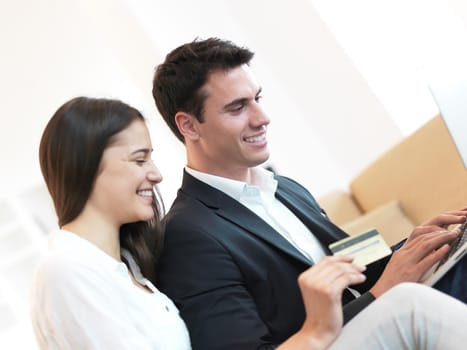 happy young relaxed  couple working on laptop computer at modern home interior