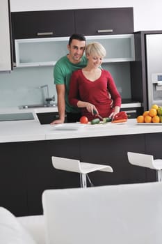 happy young couple have fun in  modern kitchen indoor  while preparing fresh fruits and vegetables food salad