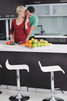 happy young couple have fun in  modern kitchen indoor  while preparing fresh fruits and vegetables food salad